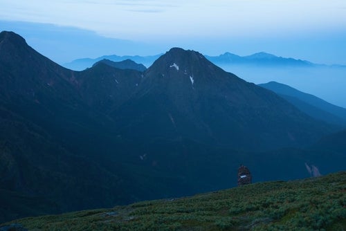 硫黄岳のケルンと霞がかる阿弥陀岳の写真