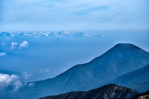 霞ゆく蓼科山と後立山連峰の写真