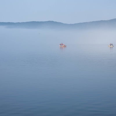 霧の芦ノ湖に浮かぶ釣り船の写真