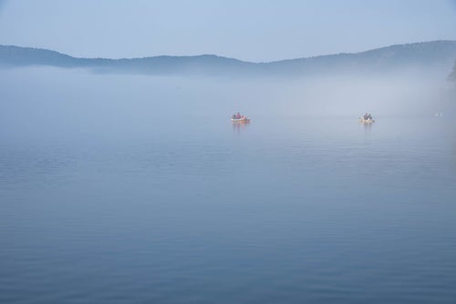 霧の芦ノ湖に浮かぶ釣り船の写真