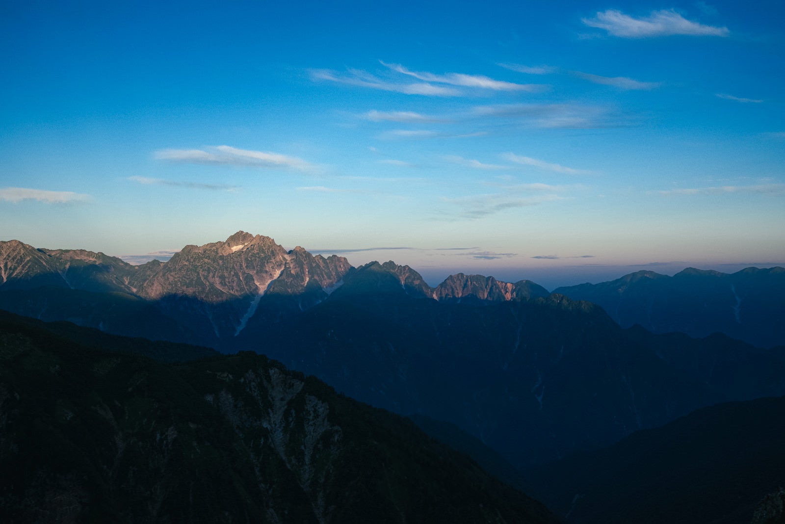 「朝日を迎える山頂部分と影」の写真