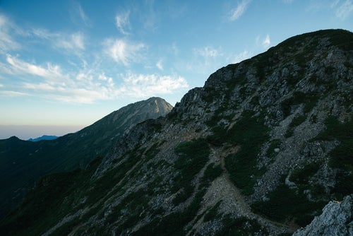 岩稜の傾斜面から続く登山道の写真
