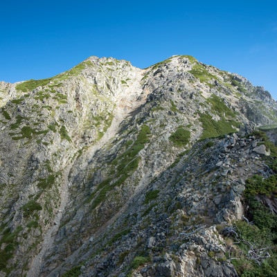 聳える岩尾根と登山道の写真