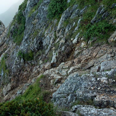 崖沿いを進む登山道の写真