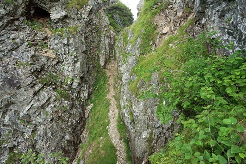崖の壁に挟まれた登山道の写真