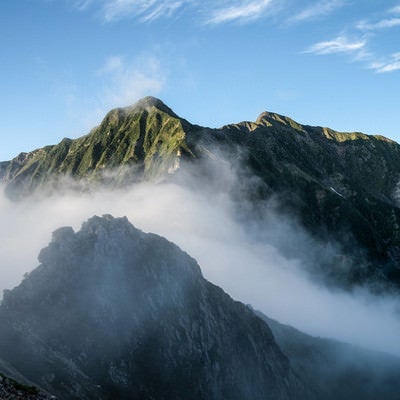 雲に隠れた岩稜と聳える稜線の写真