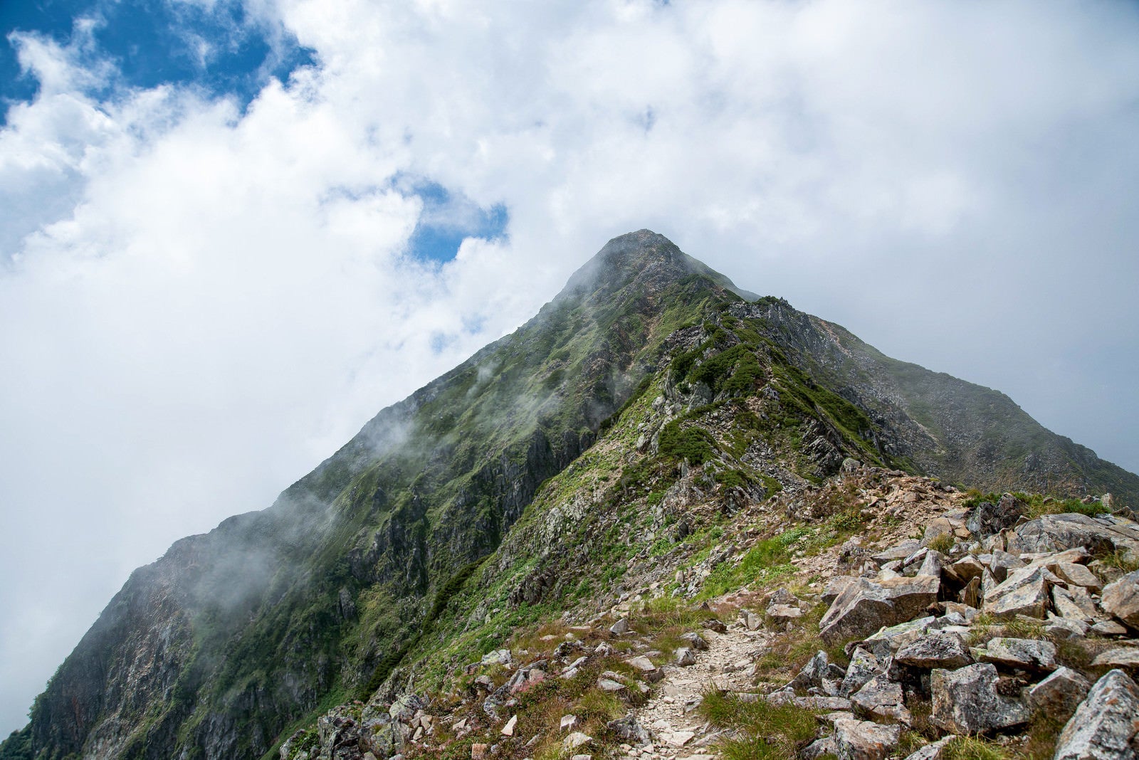 「雲かかる山頂へと続く登山道」の写真
