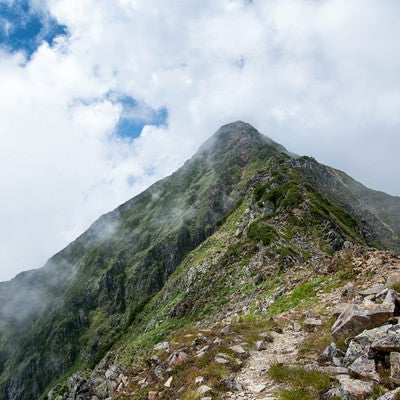 雲かかる山頂へと続く登山道の写真