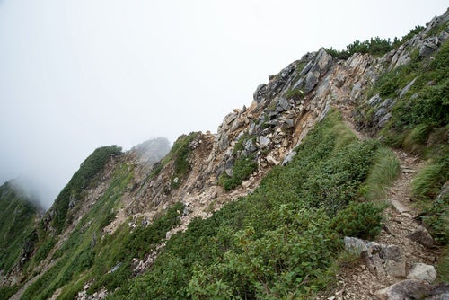 雲の壁に突き進む登山道の写真