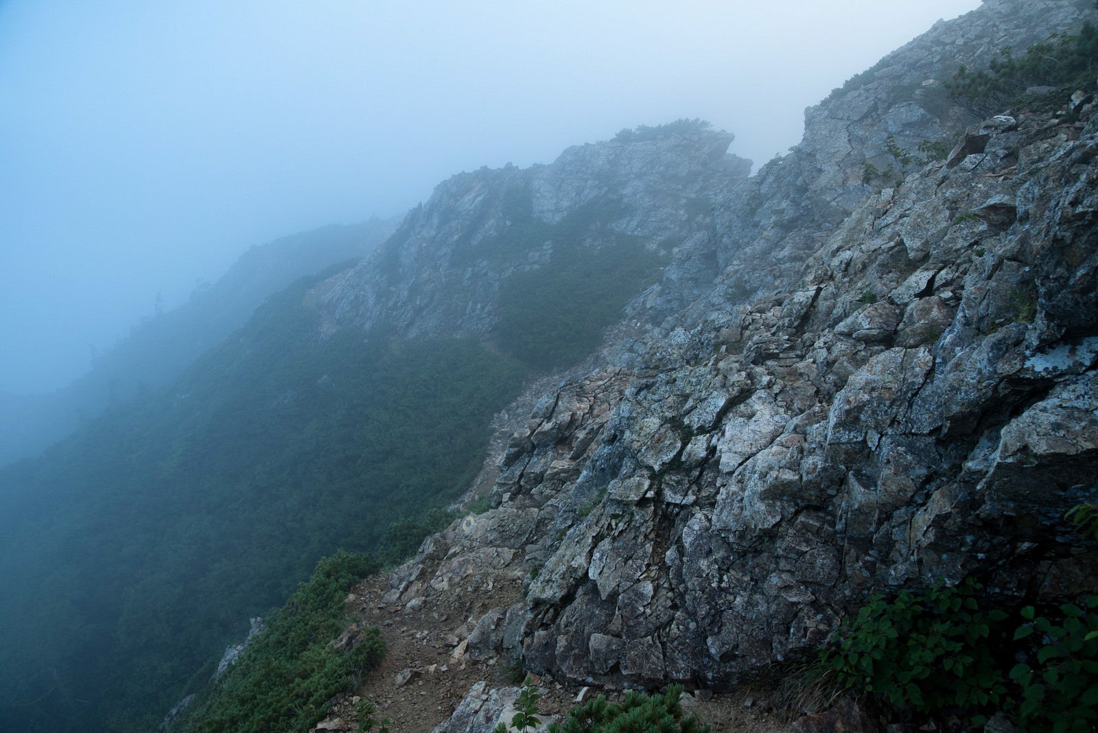 「朝霧と岩稜沿いの登山道」の写真