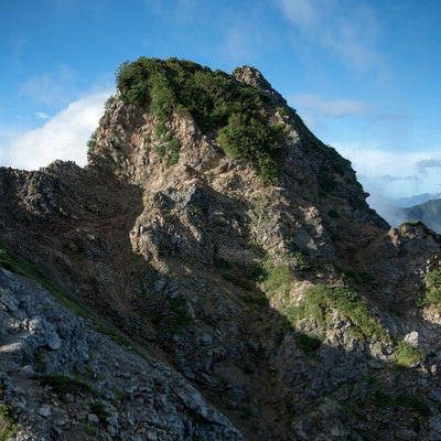 空に突き出す岩石と登山道の写真