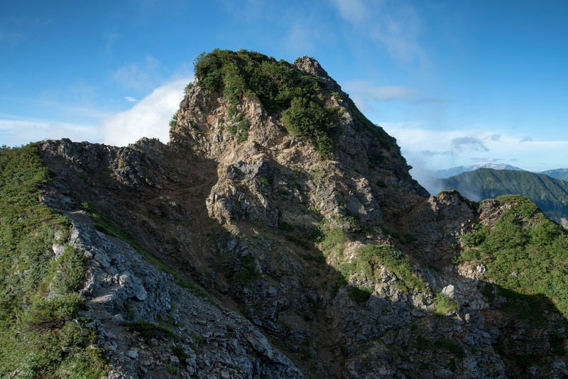 空に突き出す岩石と登山道の写真