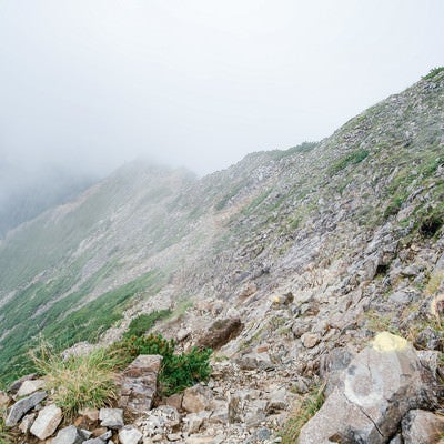 雲に覆われるガレの続く登山道の写真