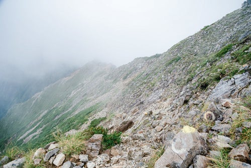 雲に覆われるガレの続く登山道の写真