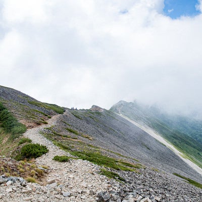 雲の中に消えゆく登山者と稜線の写真