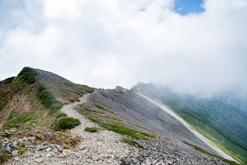 雲の中に消えゆく登山者と稜線の写真