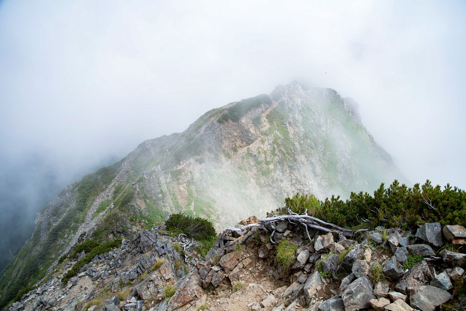 「沸き立つ雲に覆われる足場の悪い登山道」の写真