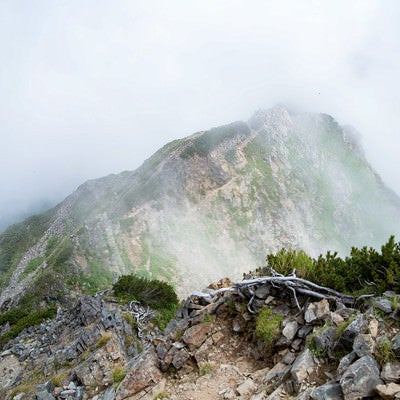 沸き立つ雲に覆われる足場の悪い登山道の写真