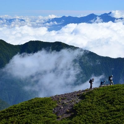 山間の雲と登山道を歩く人の写真