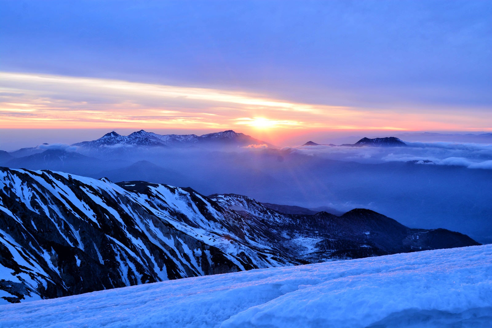 「雪山から拝む日の出」の写真