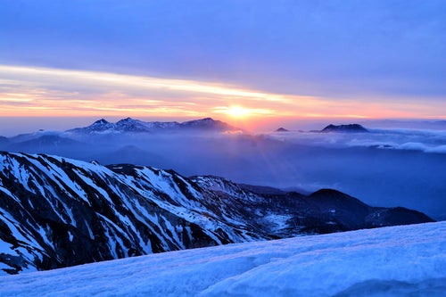 雪山から拝む日の出の写真