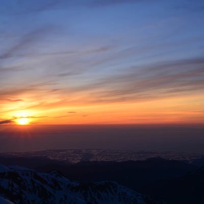 残雪の山から見る日本海に沈む夕日の写真