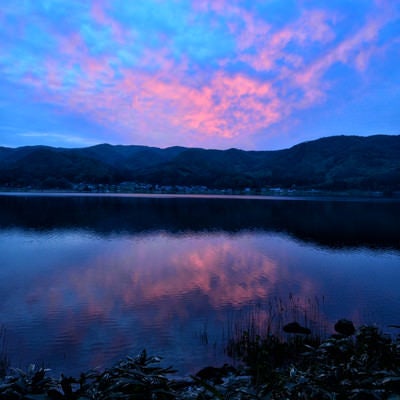 湖面に映るリフレクションした夕焼けの空の写真