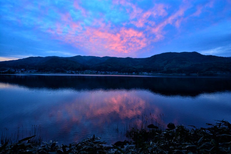 湖面に映るリフレクションした夕焼けの空の写真