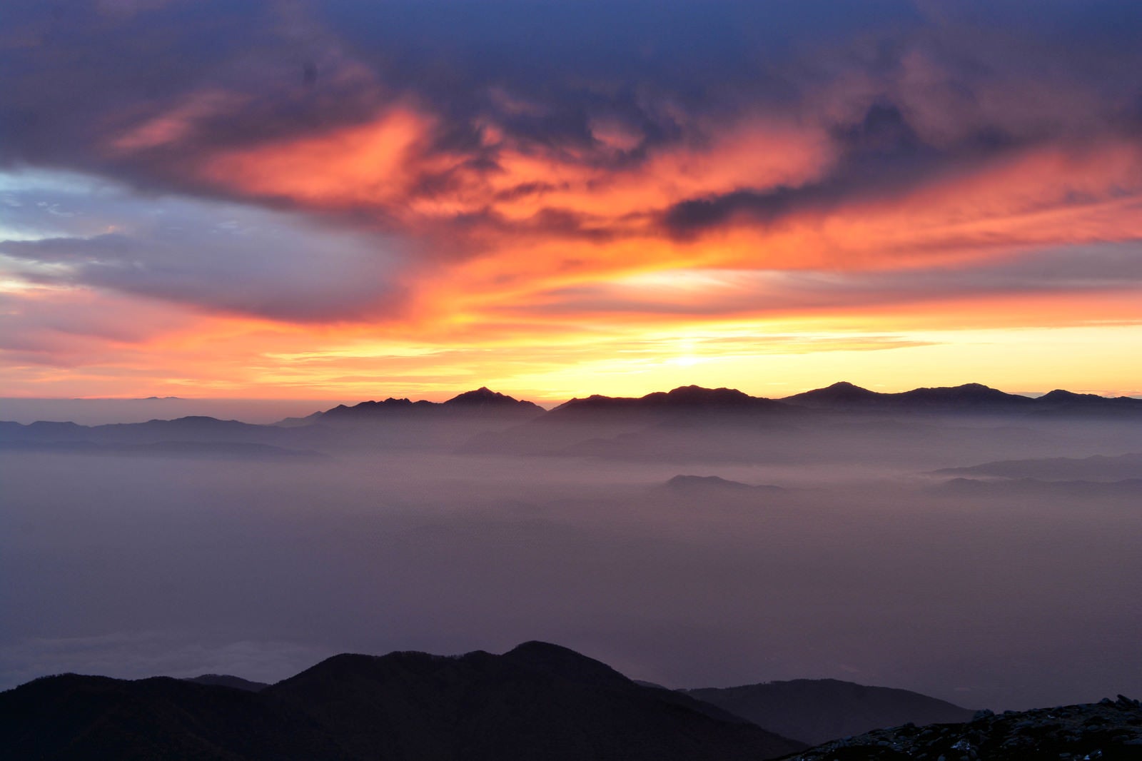 「夕焼けに染まる南アルプスのシルエットと雲海の様子」の写真