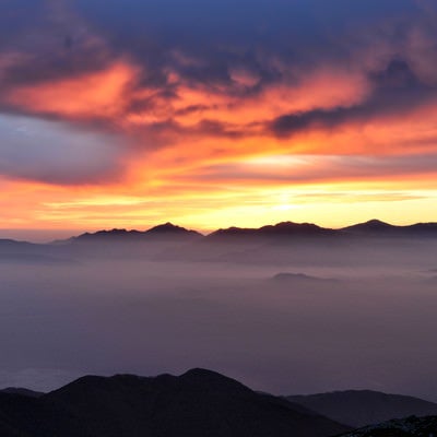 夕焼けに染まる南アルプスのシルエットと雲海の様子の写真