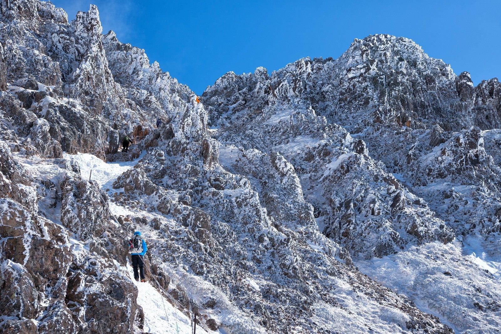 「岩と氷の山に挑戦する登山者」の写真