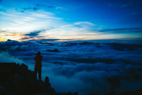 朝焼けと雲海を望む山岳カメラマンの写真