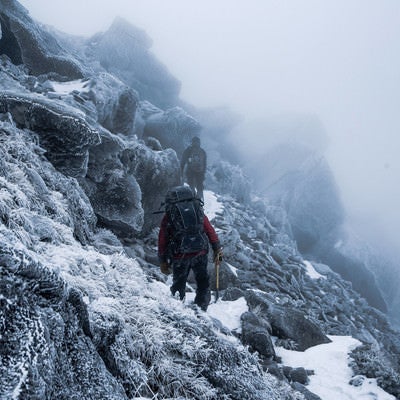 視界不良の霧の雪山と登山者の写真