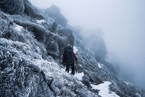 視界不良の霧の雪山と登山者の写真