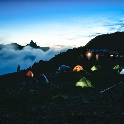 大天井岳の朝焼けとテントの灯りの写真