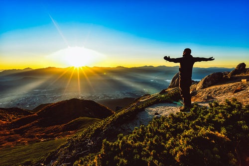 朝日を全身に浴びる登山者の写真