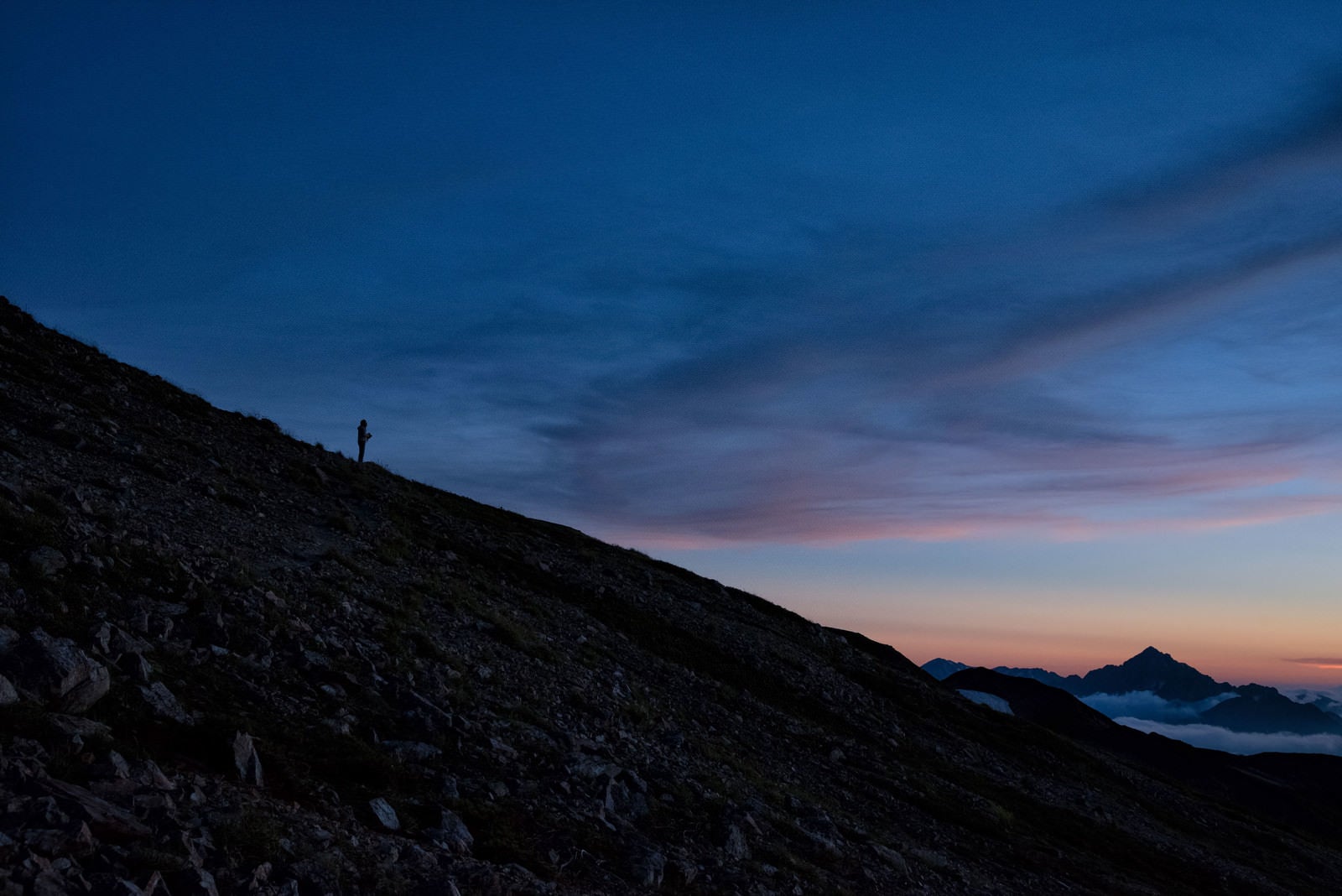 「夕焼け空と黄昏れる登山者のシルエット」の写真