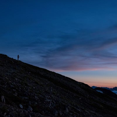 夕焼け空と黄昏れる登山者のシルエットの写真