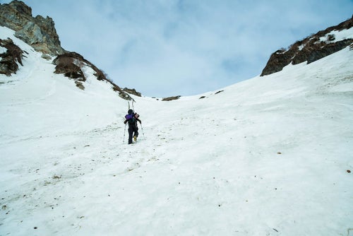 雪山の斜面を山スキーする人の写真
