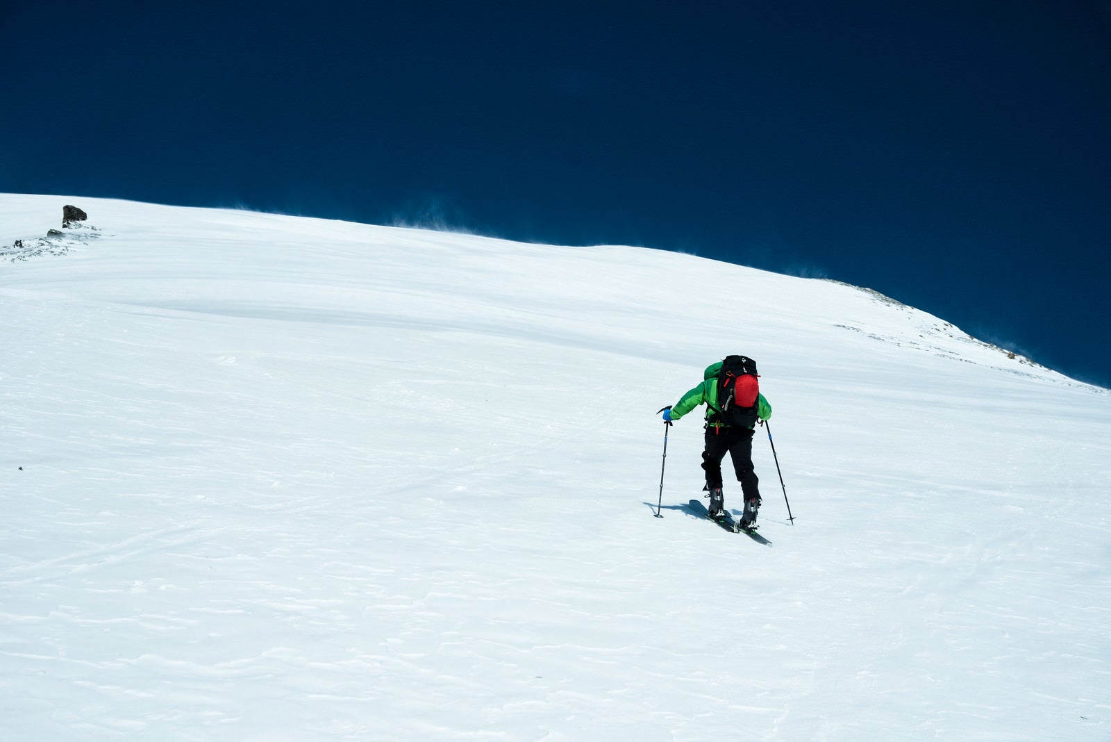 「青空に向かって歩みを進めるスキーヤー」の写真