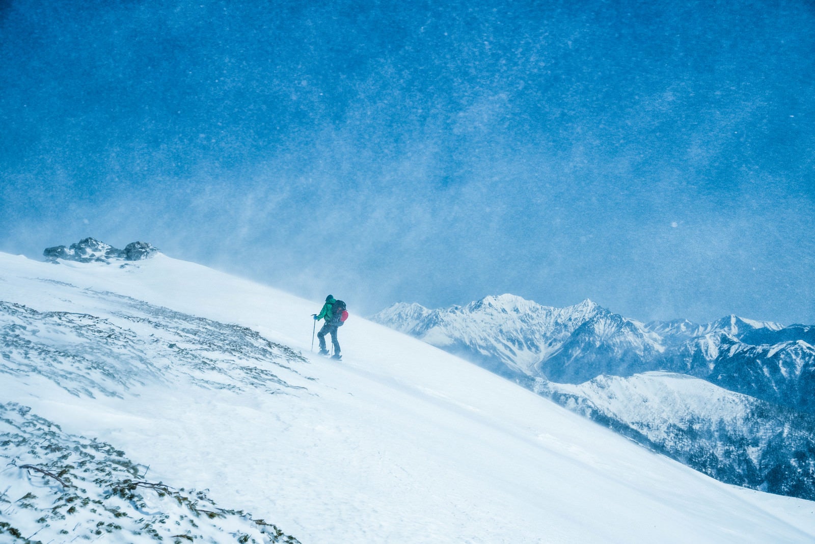 「舞い上がる雪と山スキーヤー」の写真