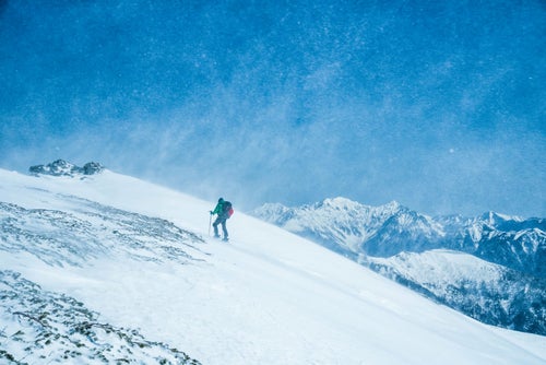 舞い上がる雪と山スキーヤーの写真