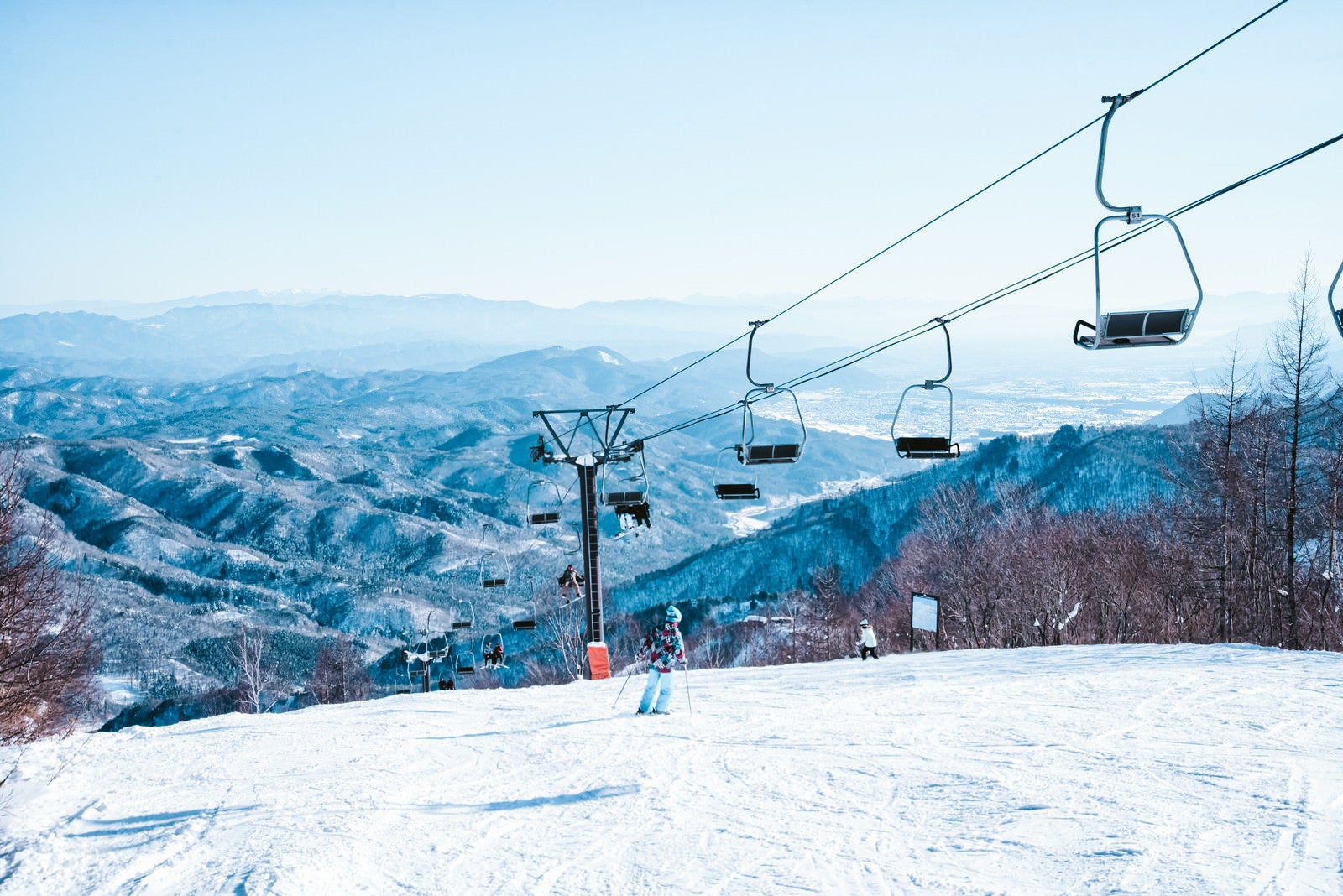 「ゲレンデを滑るスキーヤーとリフト」の写真