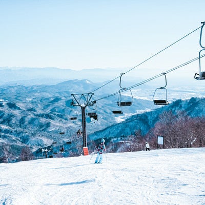 ゲレンデを滑るスキーヤーとリフトの写真