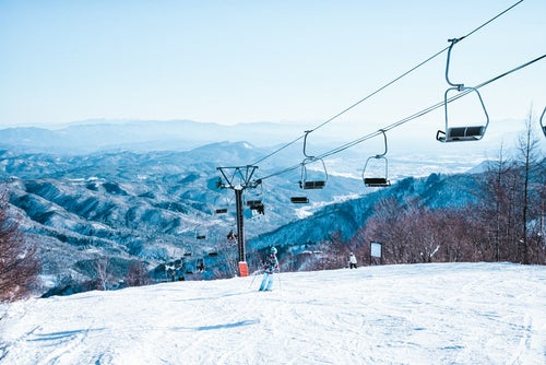 ゲレンデを滑るスキーヤーとリフトの写真