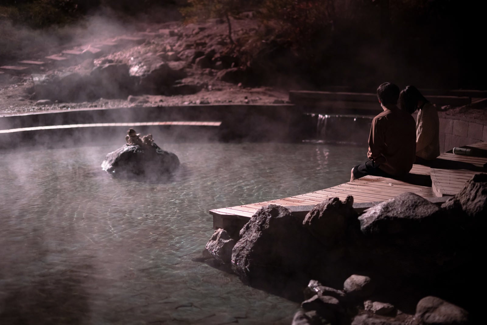 「西の河原公園で足湯に浸かる男女」の写真