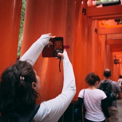 伏見稲荷大社・千本鳥居をスマホで撮影する外国人観光客の写真