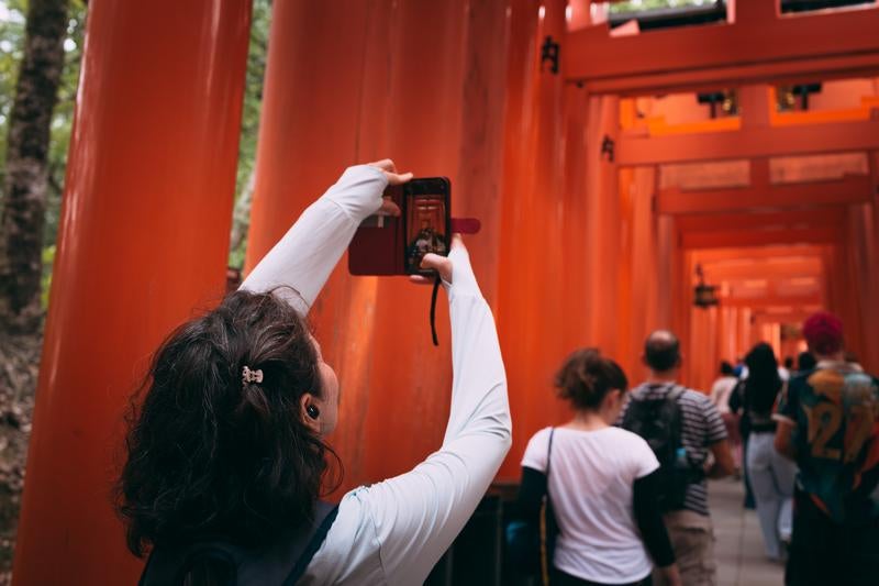 伏見稲荷大社・千本鳥居をスマホで撮影する外国人観光客の写真