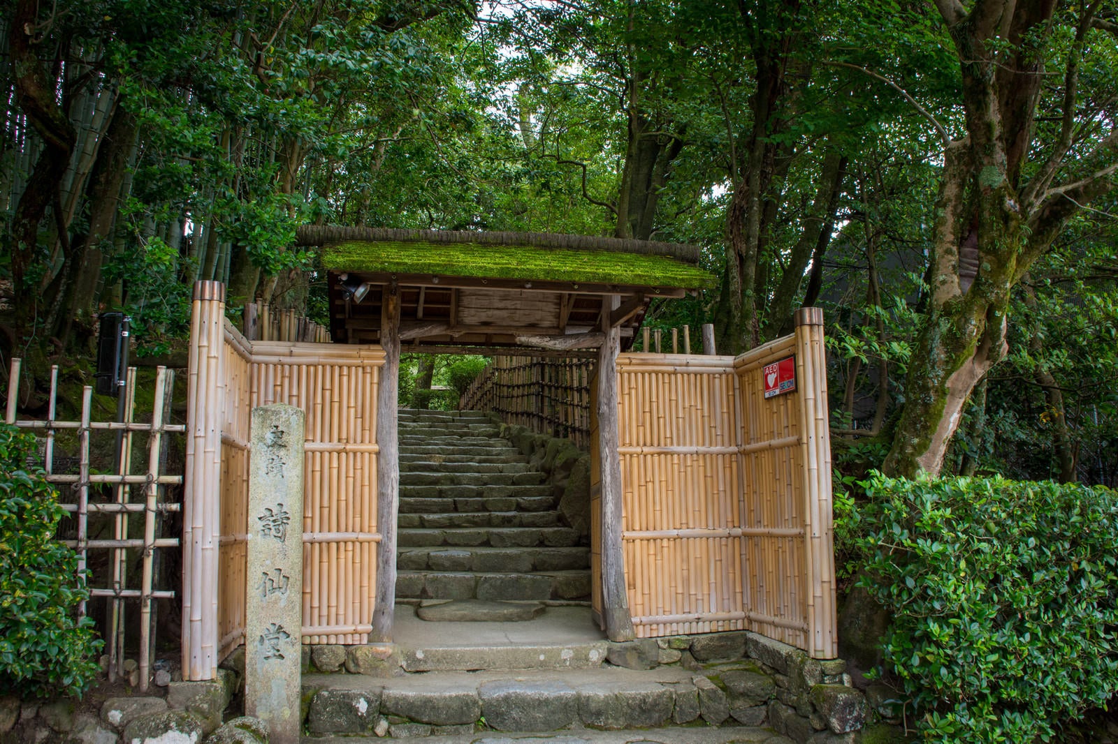 「竹垣と苔むした屋根が迎えてくれる京都詩仙堂入り口」の写真