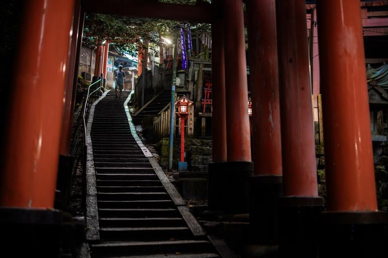 夜の伏見稲荷大社で連なる朱色の鳥居と石段の写真